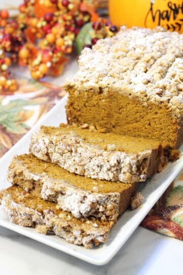 Sliced maple pumpkin bread with closeup of front slices on white platter.