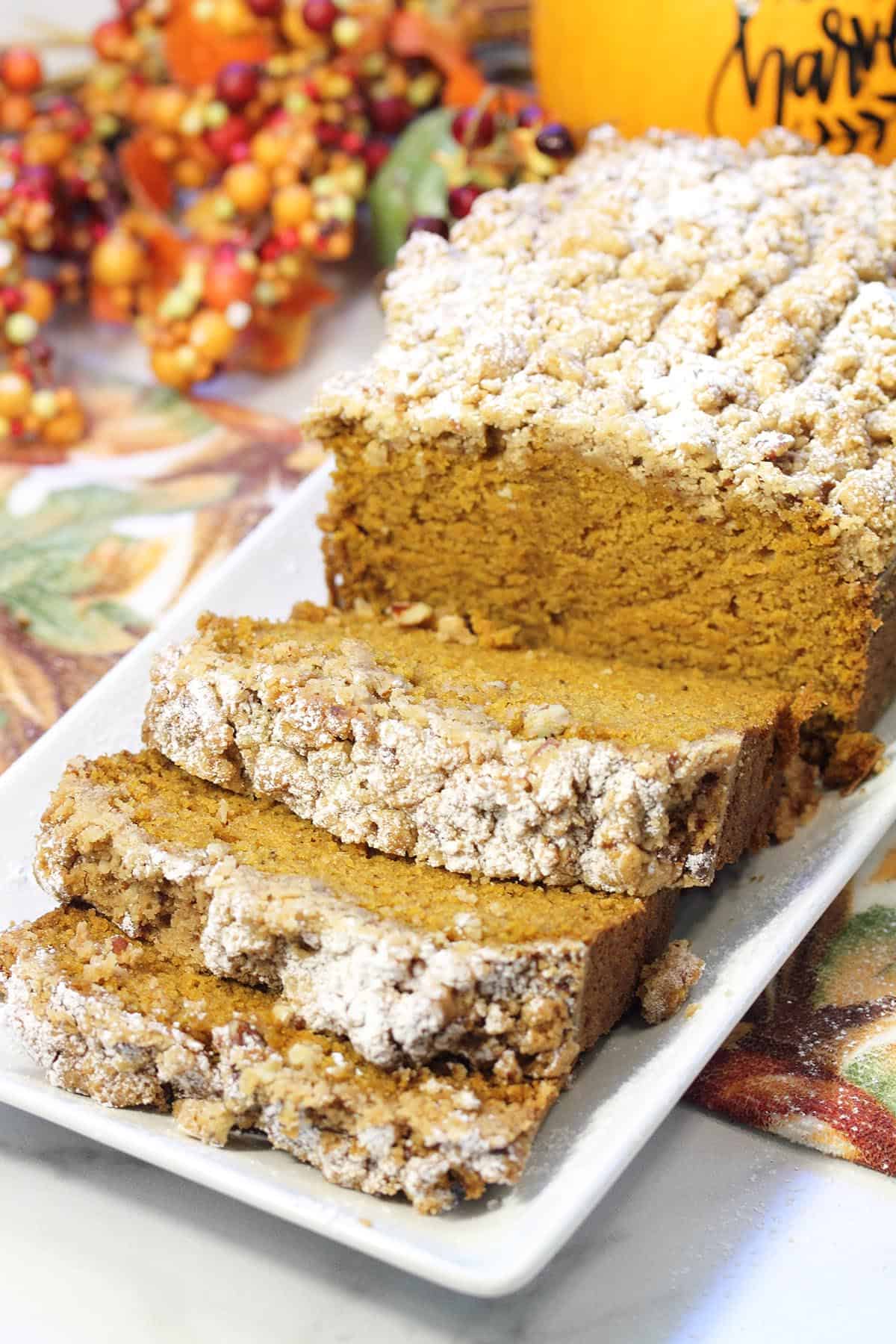 Sliced maple pumpkin bread with closeup of front slices on white platter.