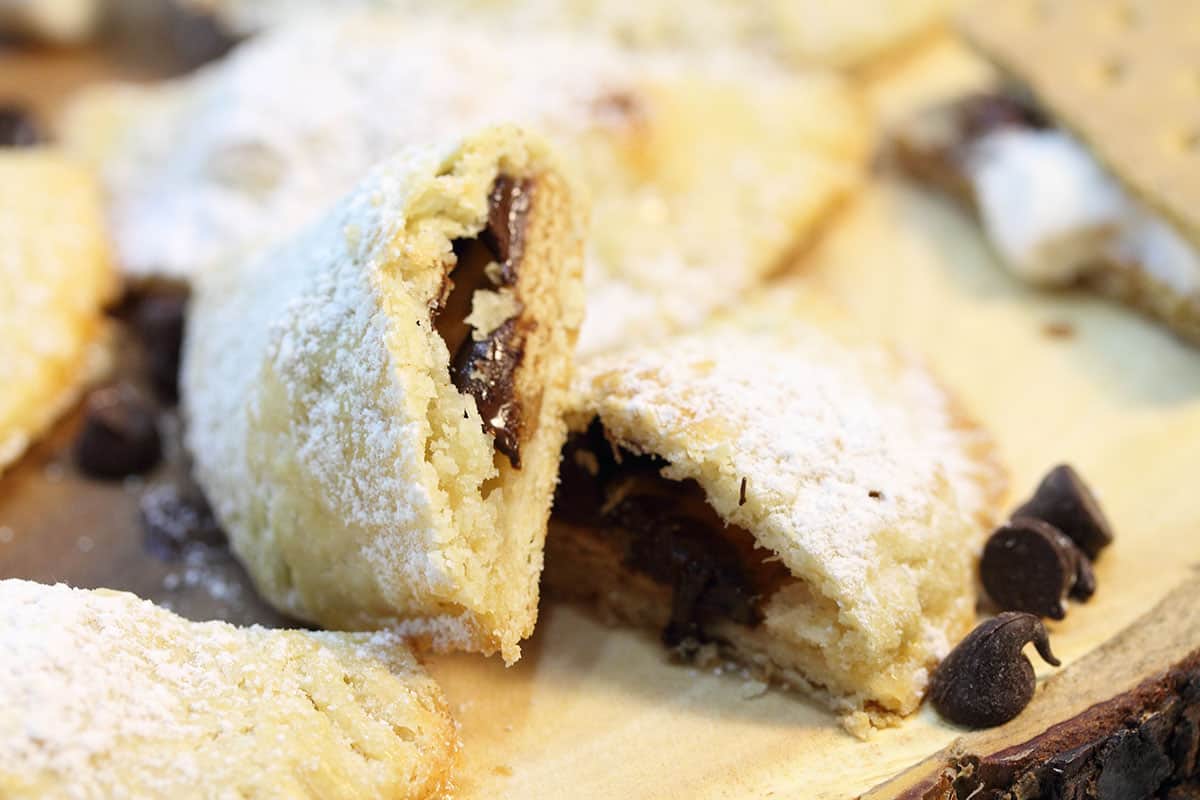 Closeup of halved pastry on wooden board with chocolate chips around it.