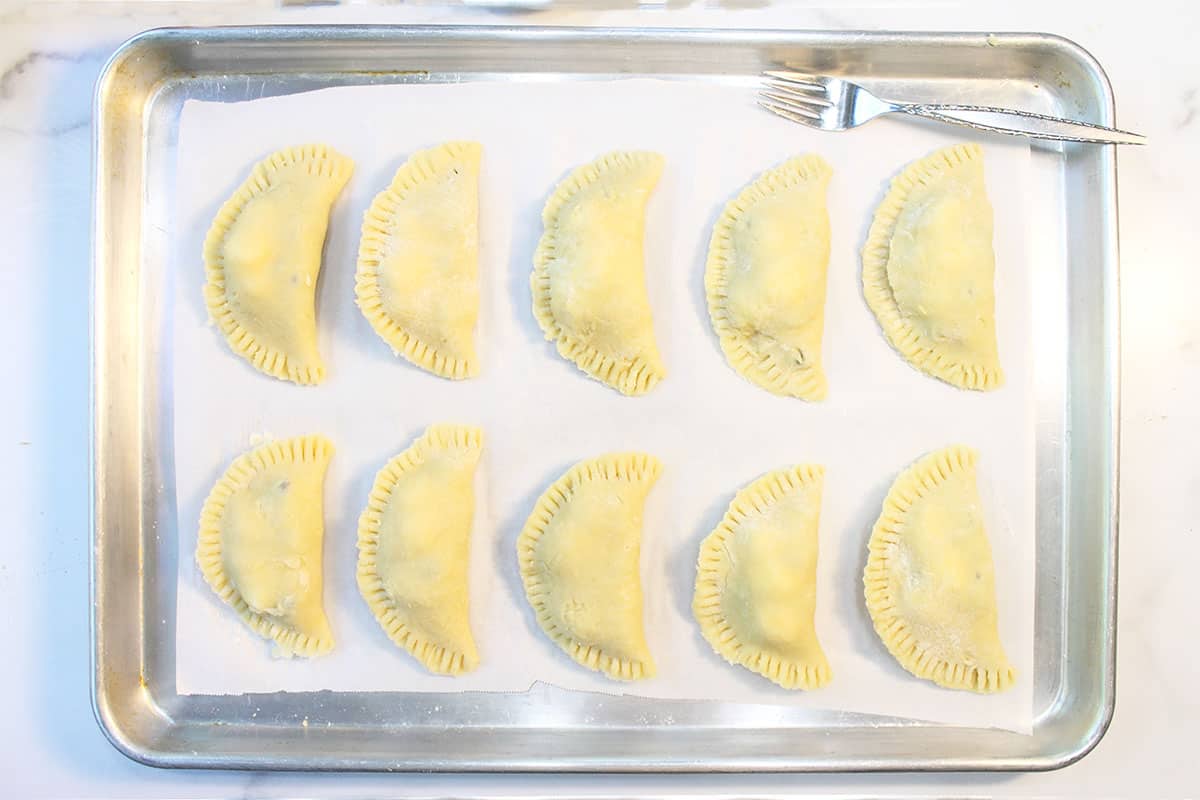 Empanada edges pressed with tines of fork and ready to bake.