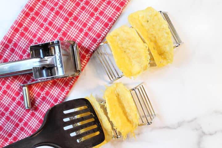 Forming taco shells by pushing into taco holder with spatula.