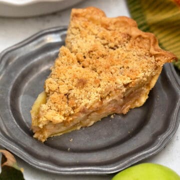 Slice of apple pie on pewter plate.