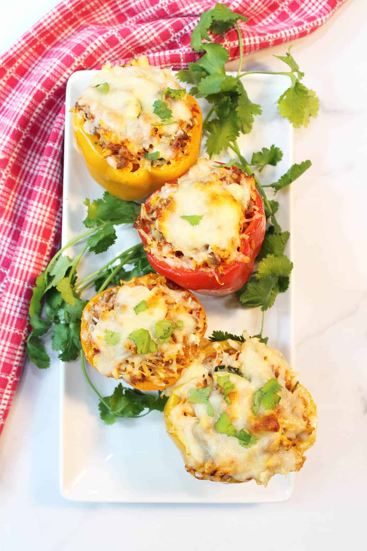 Overhead of stuffed peppers with ground beef on white serving platter.