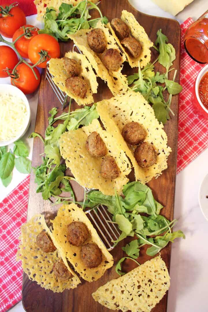Overhead of meatballs in taco shells on wooden board.