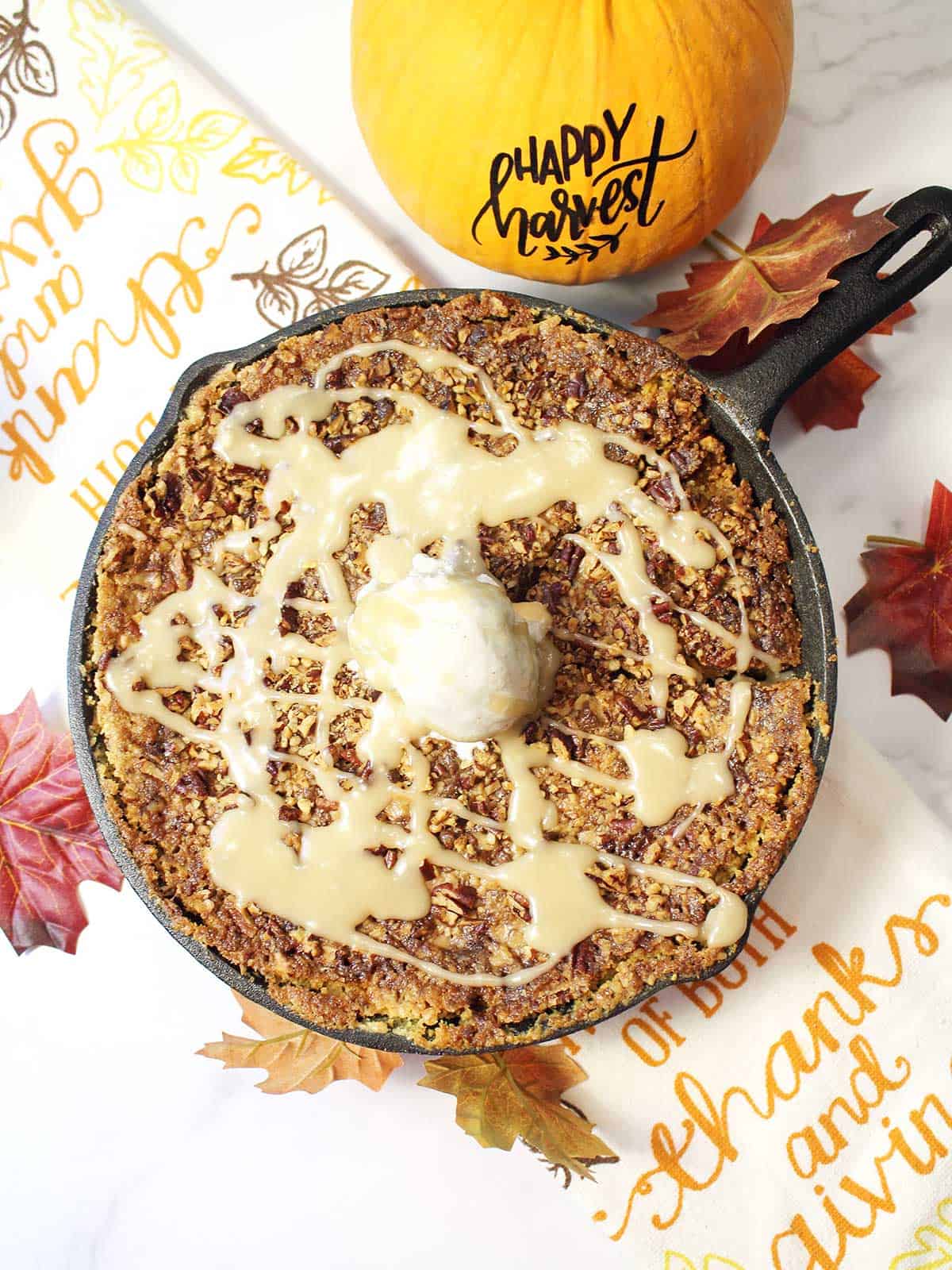 Overhead of pumpkin dump cake with yellow cake mix in skillet with maple sauce and ice cream.