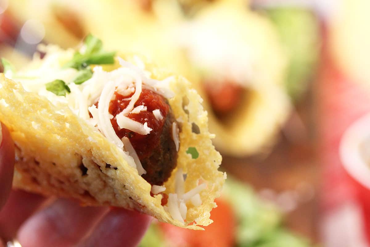 Super closeup holding taco above serving board showing inside.