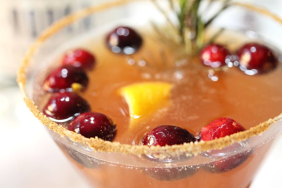 Closeup of cinnamon sugar rim and cranberries in cocktail.
