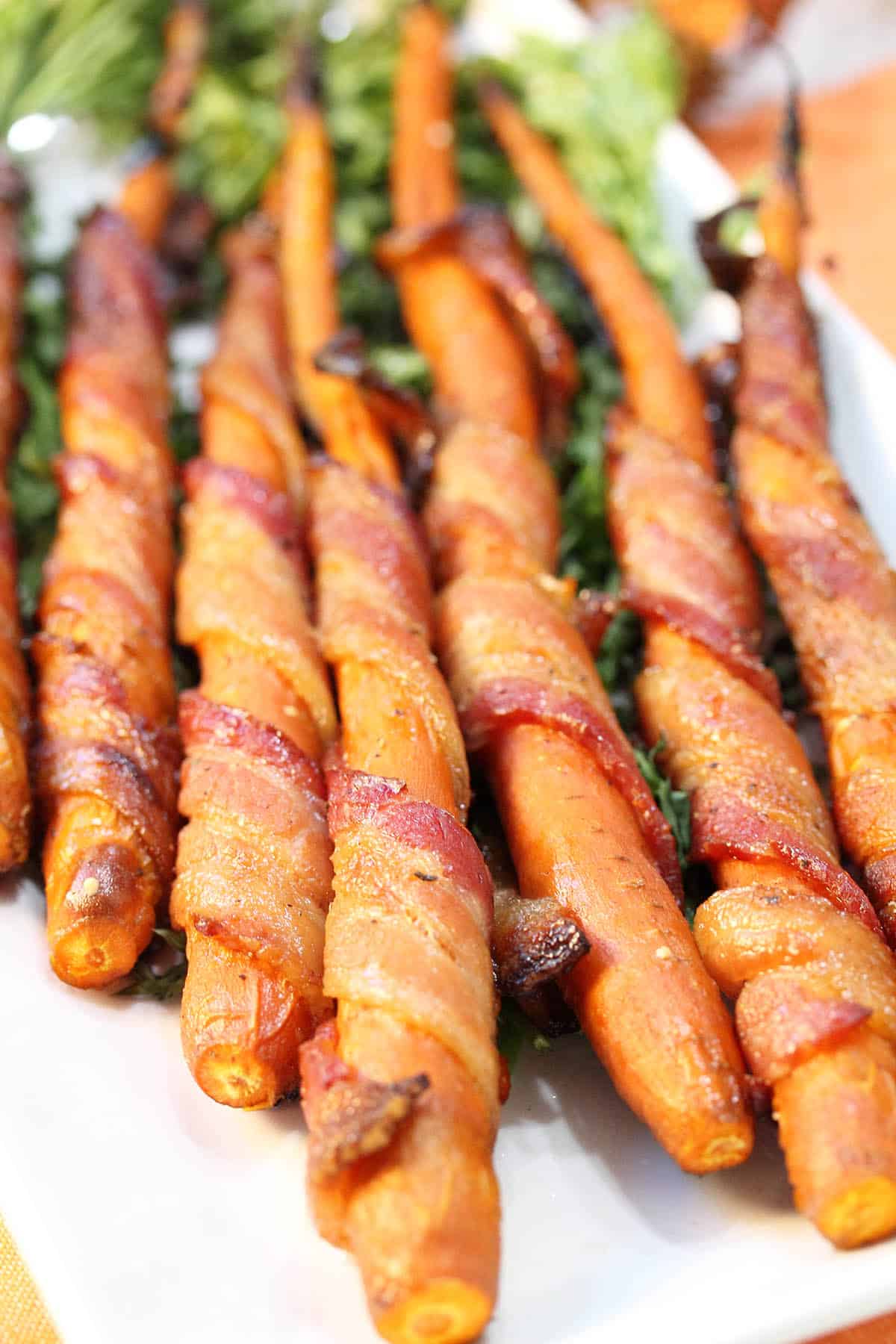 Closeup of cooked maple glazed carrots showing crispy bacon.