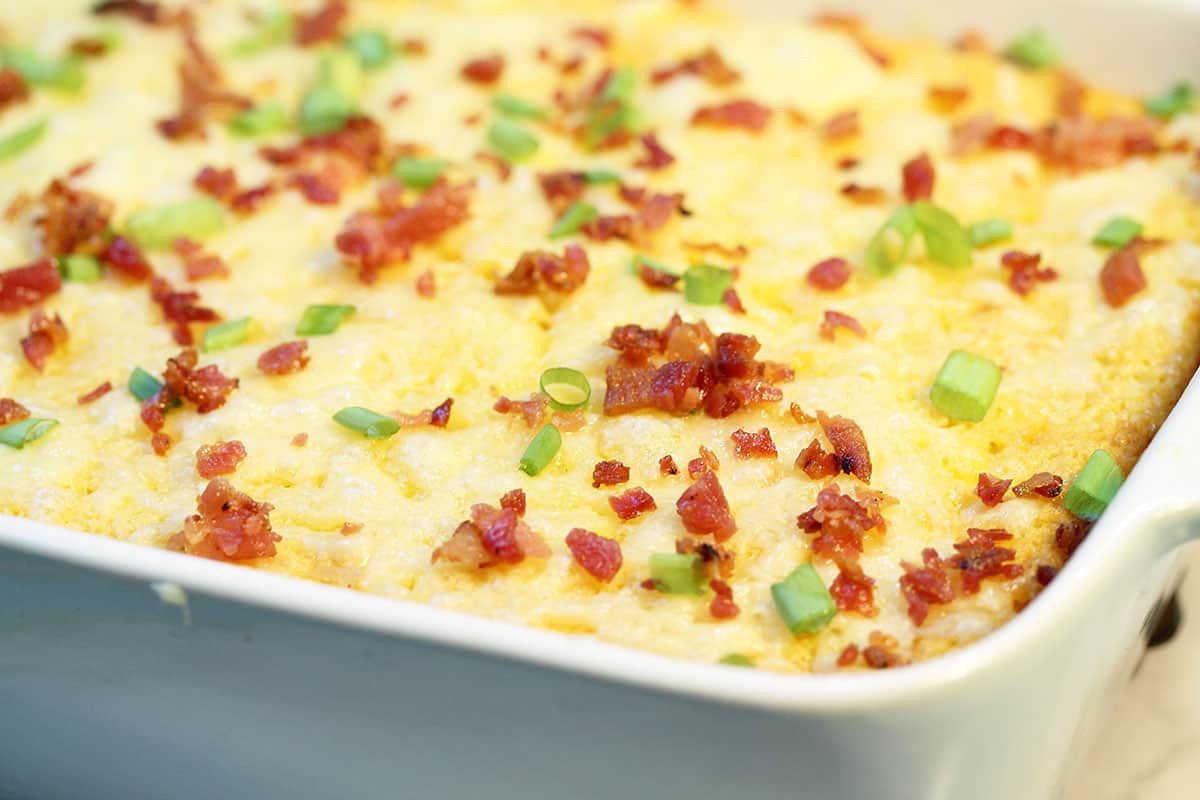 Closeup of corner of casserole showing richness of pudding and bacon garnish.