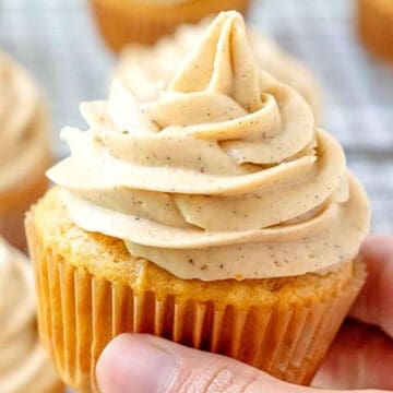 Holding a Pumpkin Cupcake with pumpkin spice cream cheese frosting.