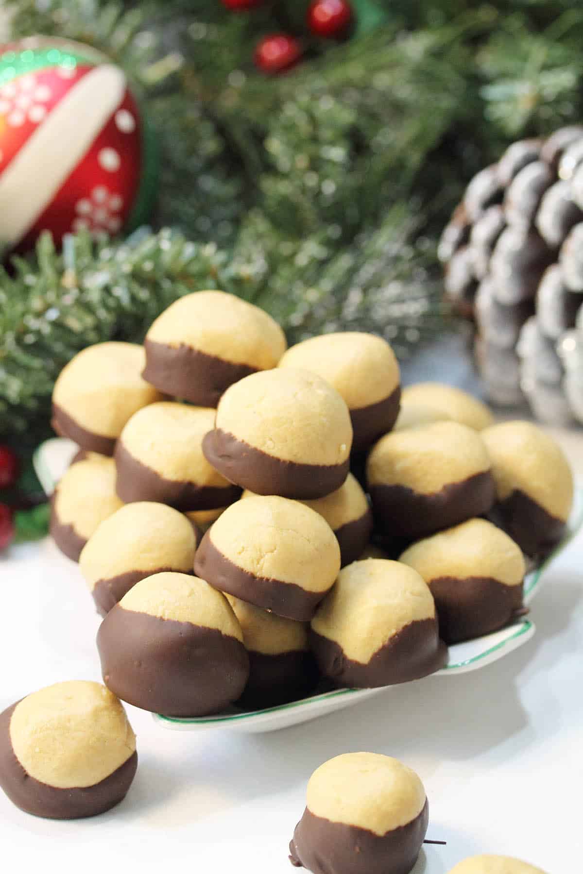 Pile of Ohio State Buckeyes on Christmas tree serving dish with greenery pine cone.