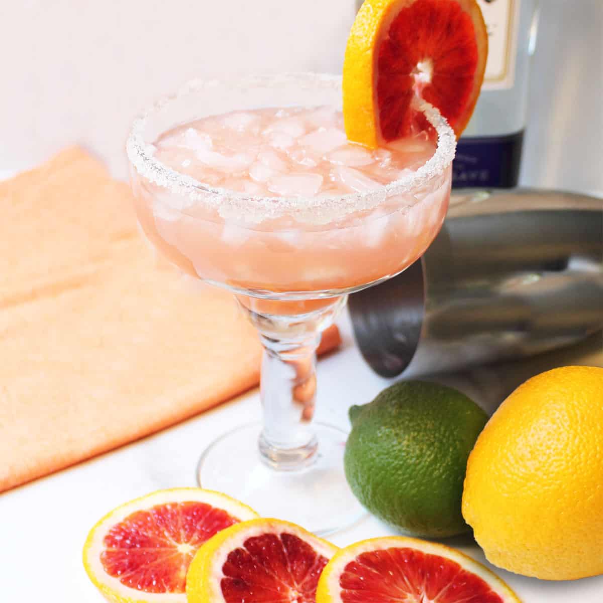 Blood Orange Margarita with blood orange and lime on white table