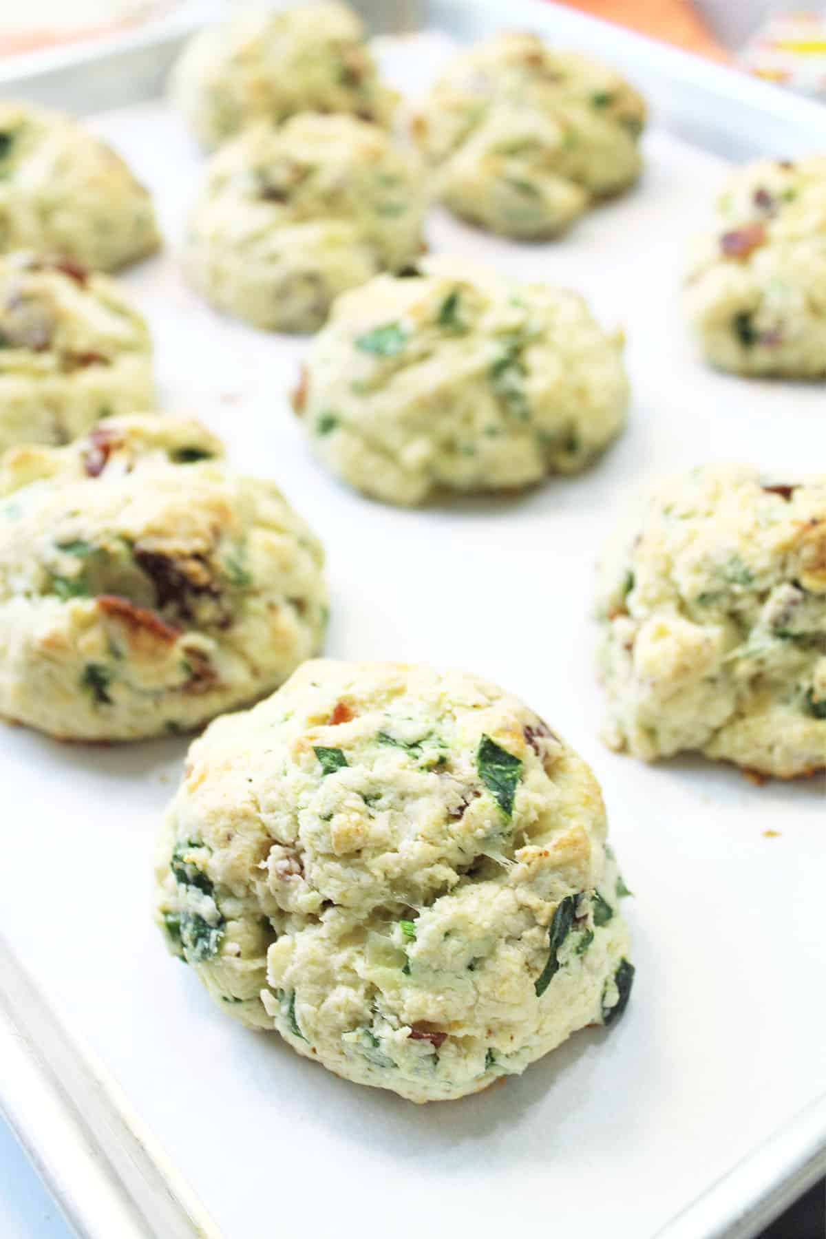 Closeup of baked cheese and bacon scones on parchment lined cookie sheet.