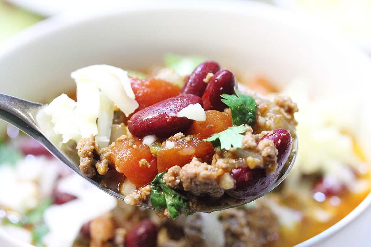 Spoonful of chili over bowl of chili.