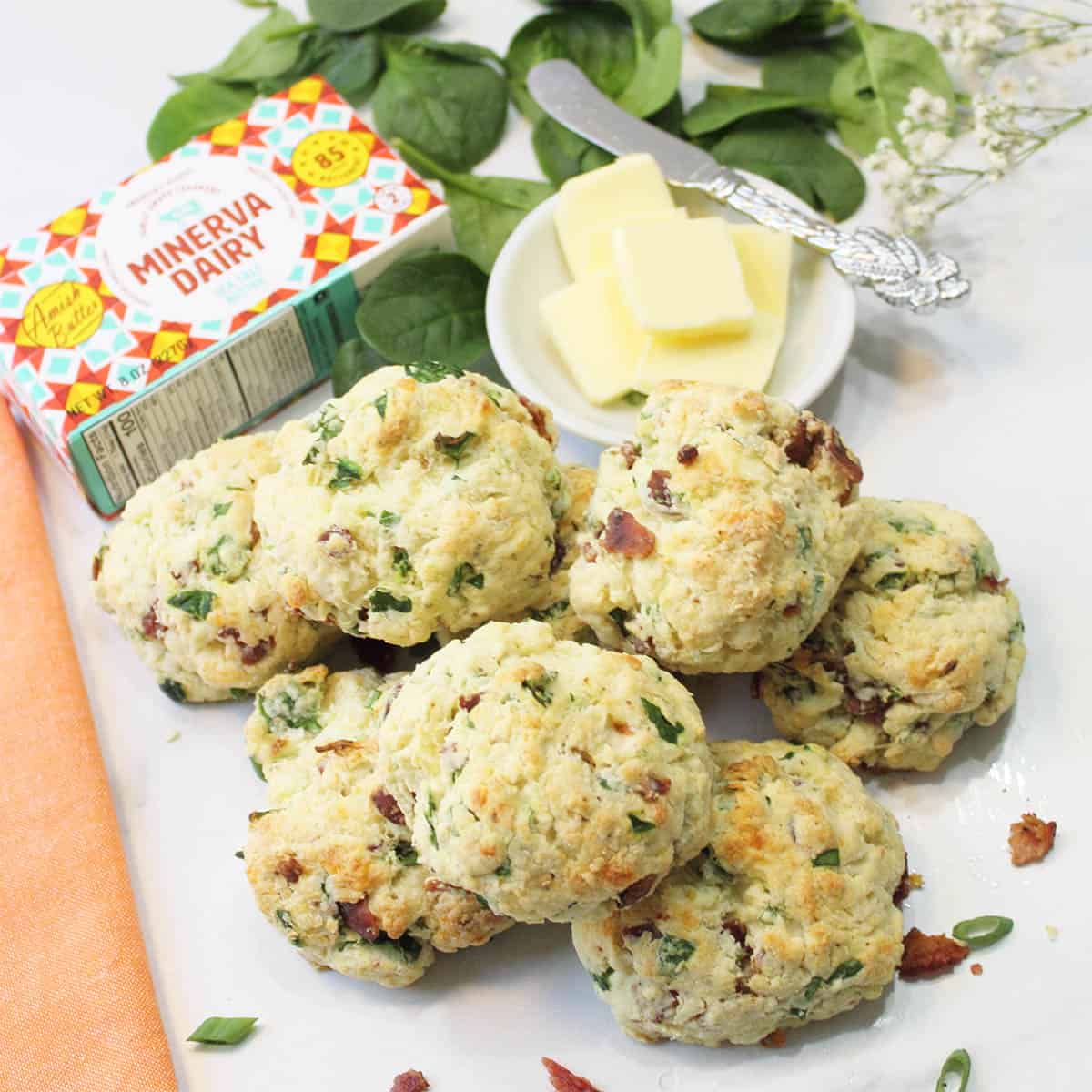 Stack of scones in front of Minerva butter package and dish of butter with butter knife.