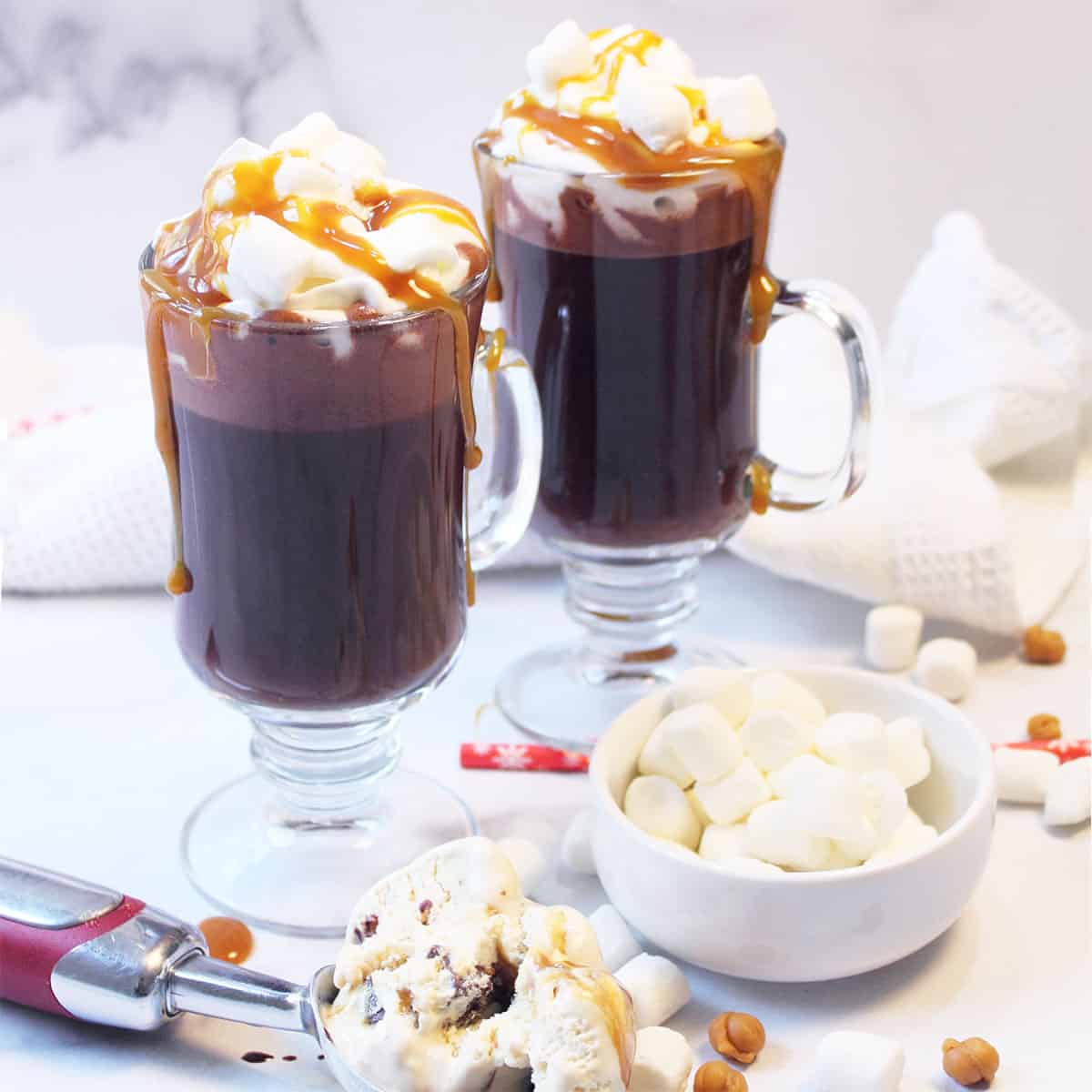 Two melted ice cream hot chocolates with caramel sauce with marshmallows on the table.