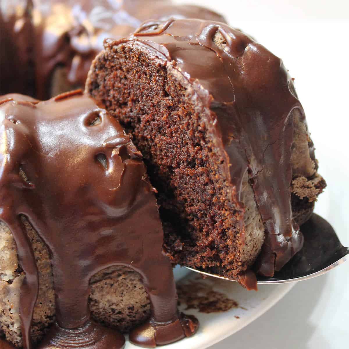 Lifting slice of cake from ganache covered chocolate pound cake.