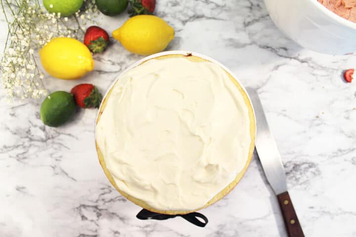 Spreading lemon cream filling on bottom cake layer.