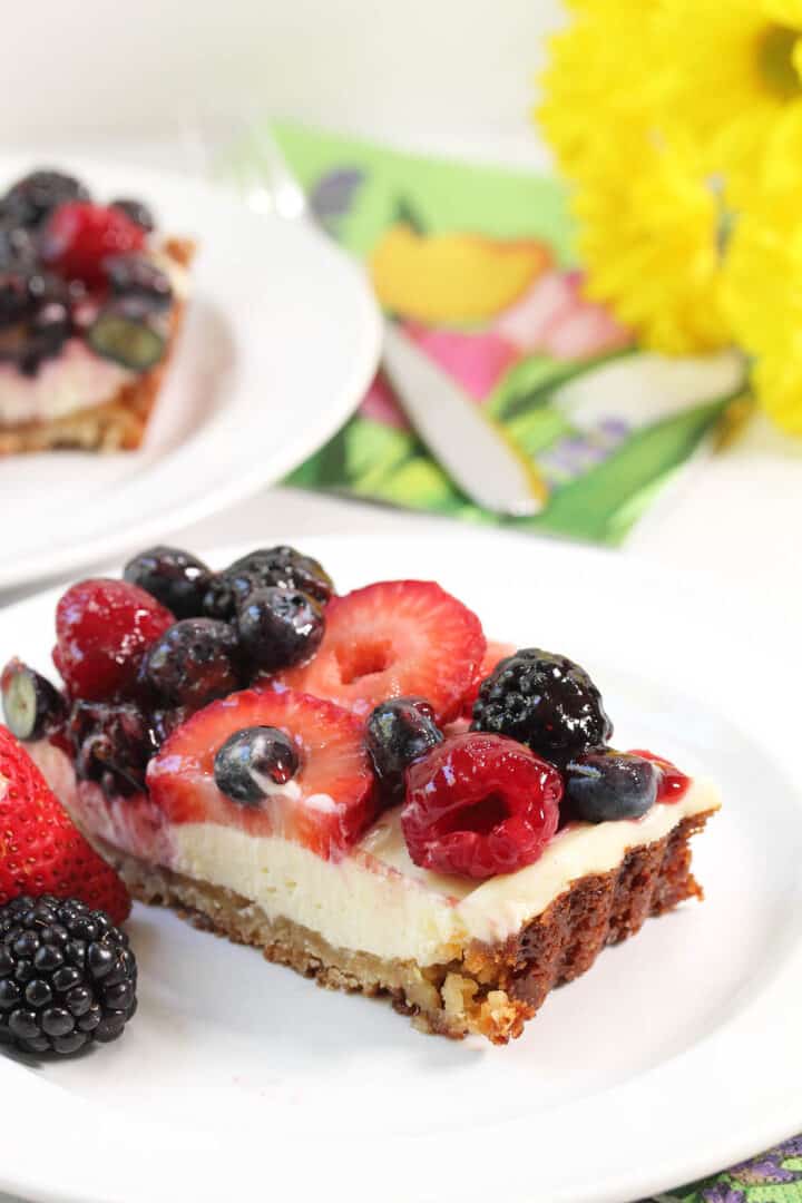 Closeup of slice of fruit topped tart on plate.