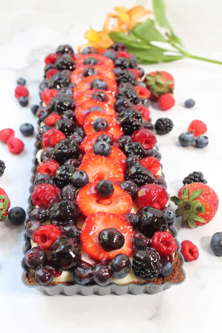 Finished fruit tart in pan on marble tabletop.