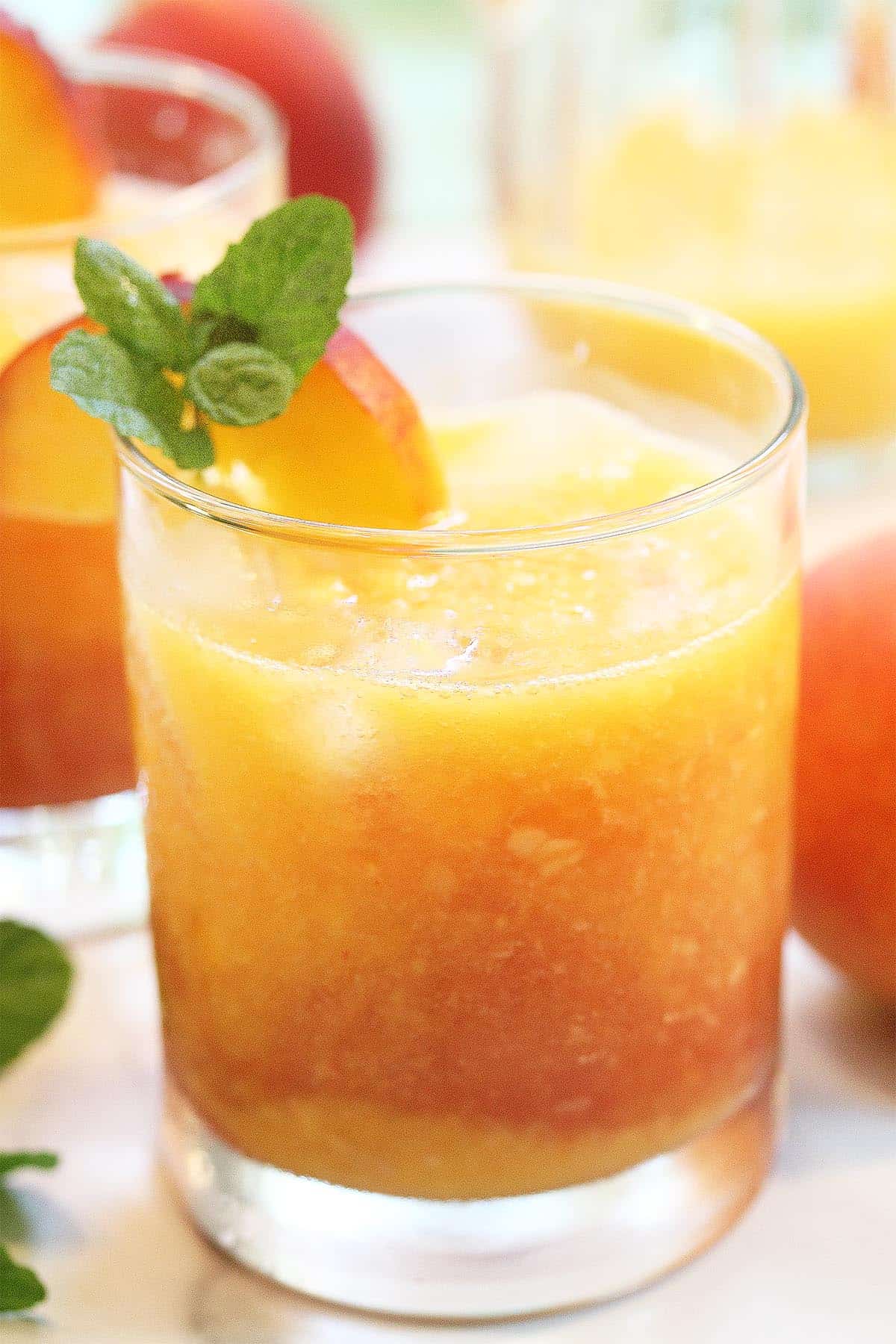 Closeup or cocktail with garnish of peach slice and mint.