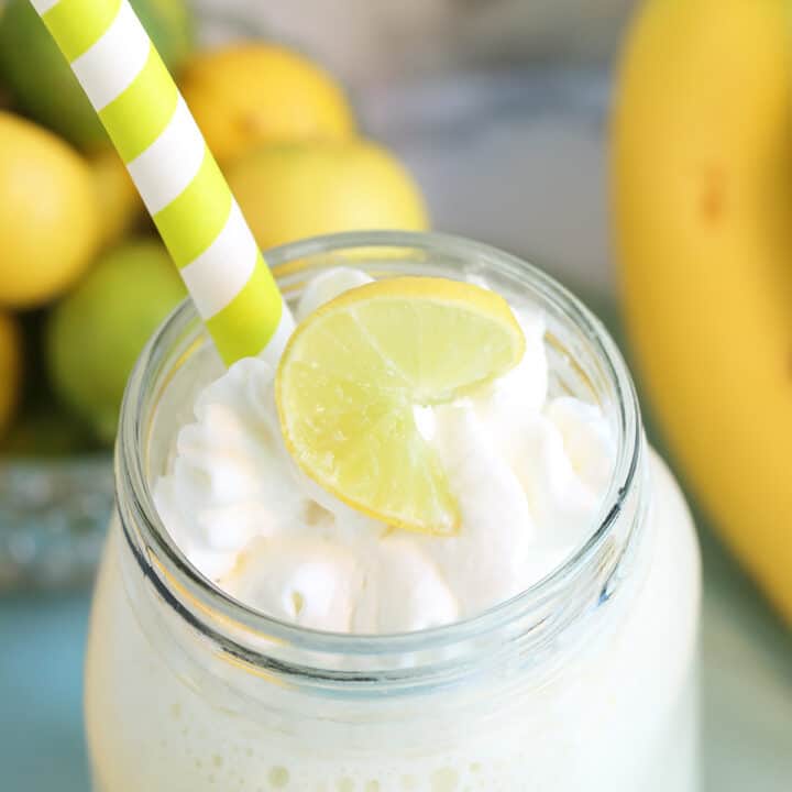 Overhead closeup of lime coconut smoothie with whipped cream, straw and lime slice.