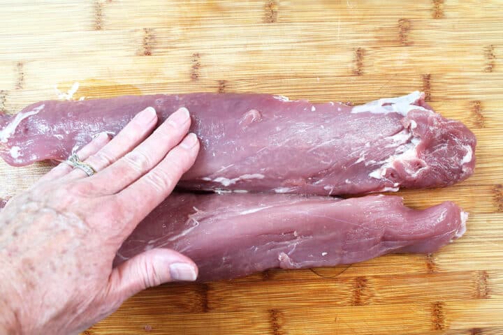 Rubbing olive oil over pork.