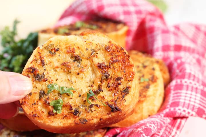 Closeup holding air fried garlic bread over basket.