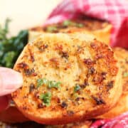 Closeup holding air fried garlic bread over basket.