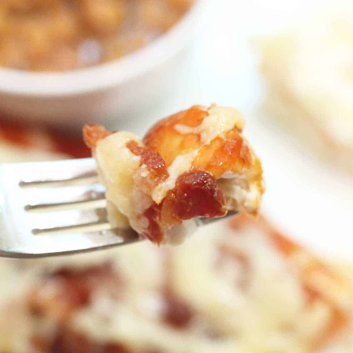 Bite of chicken on fork over plate.