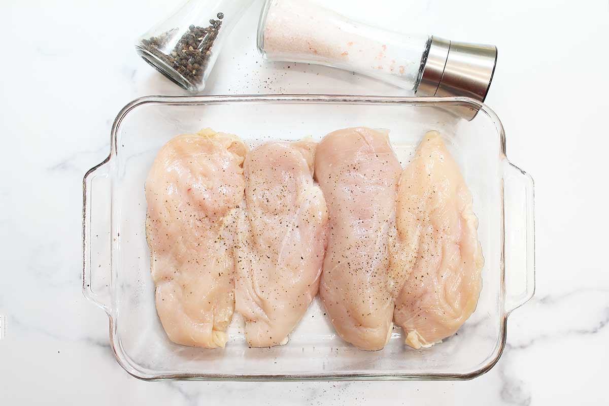 Chicken breasts in baking dish with salt and pepper seasoning.