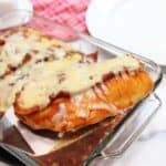 Lifting baked BBQ chicken breast from casserole.