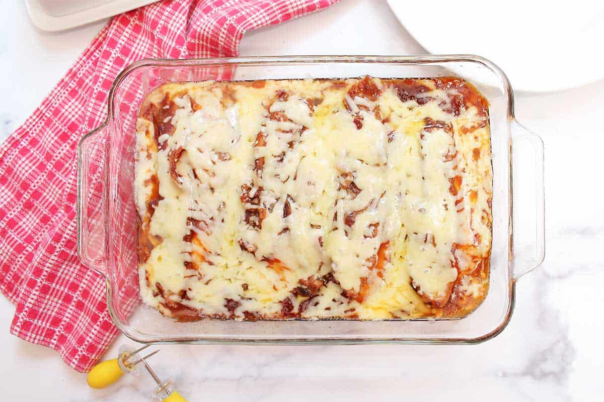 Baked boneless BBQ chicken on white table with red checkered towel.