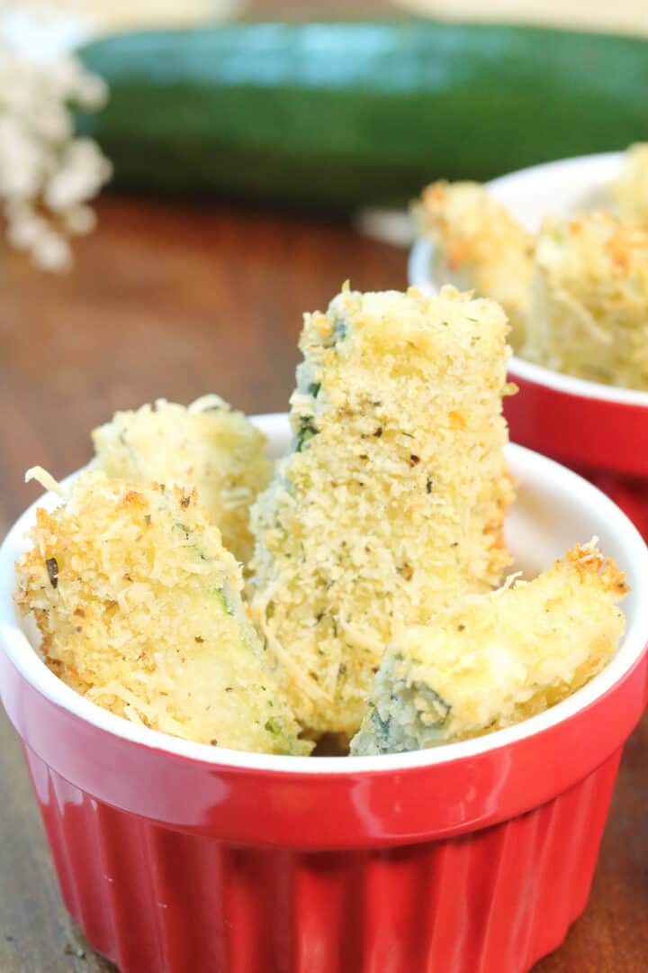 Closeup on serving fo zucchini fries in red bowl.