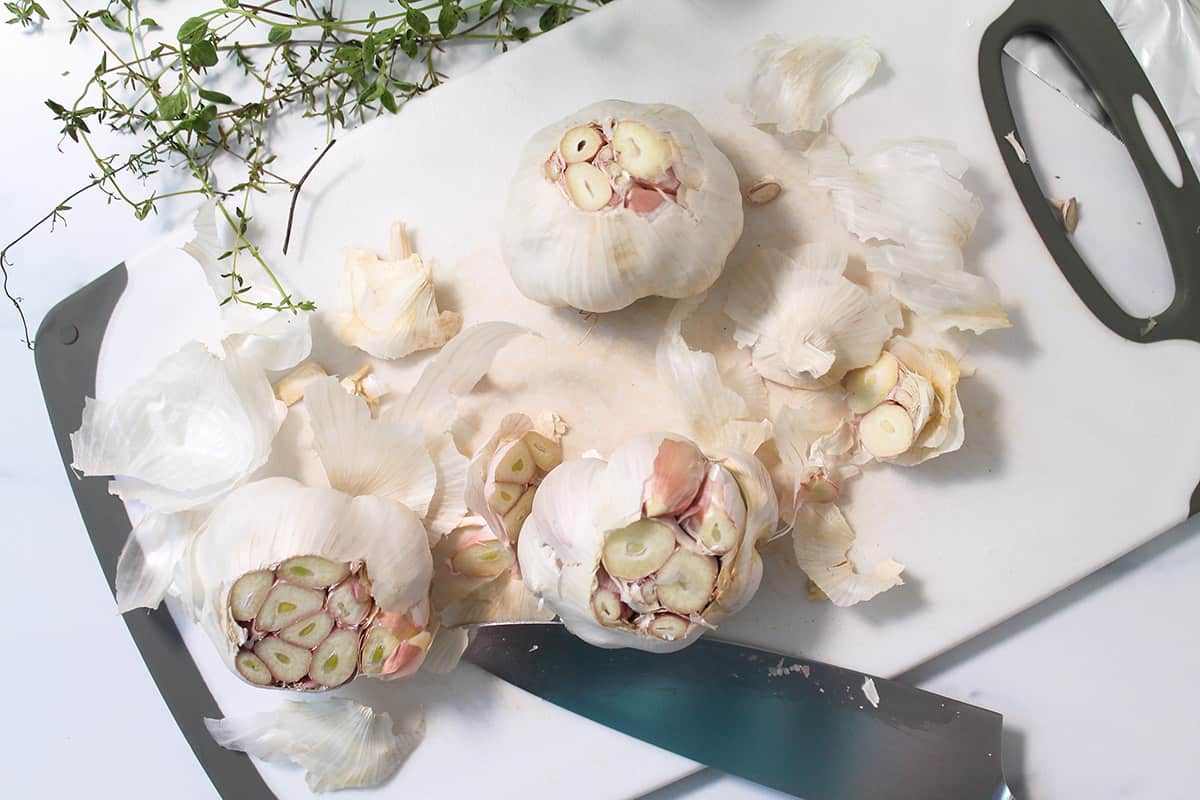 Cutting the tops off the garlic heads.