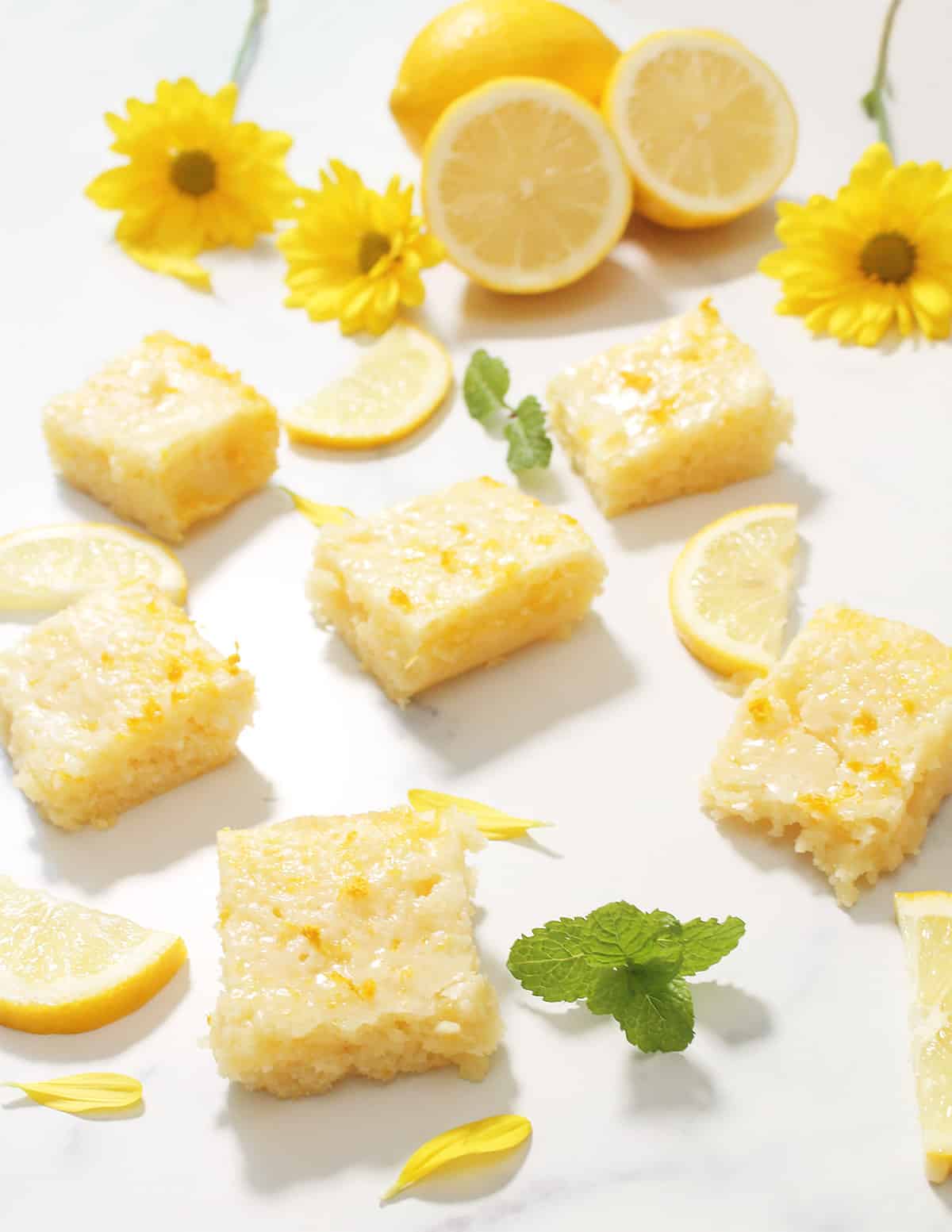Brownies on marble table with mint, flowers and halved lemons.