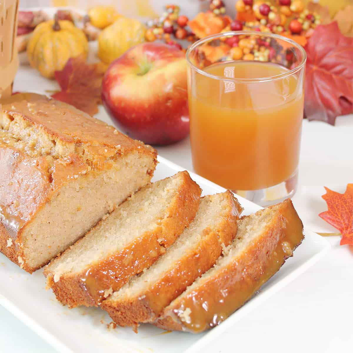 Apple Cider Donut Pound Cake sliced on platter next to apple cider.