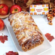 Glazed pull-apart bread on white platter with butter package.