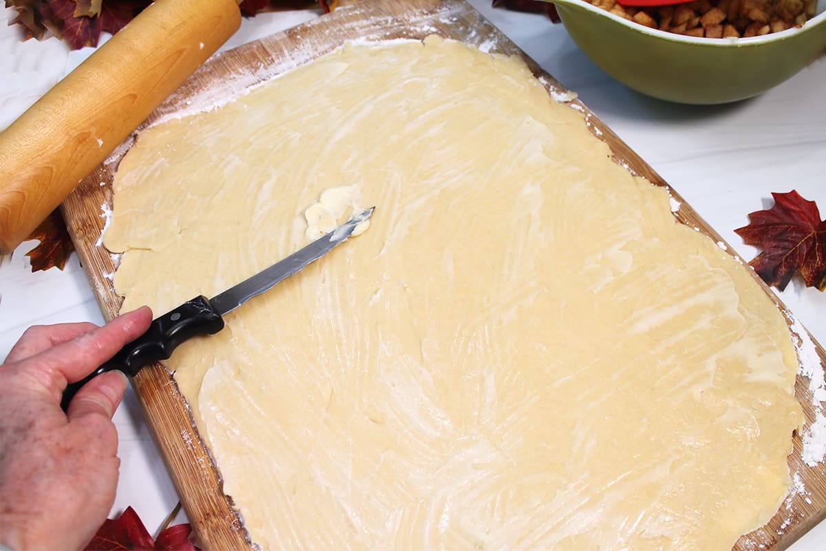 Spreading butter on rolled out dough.