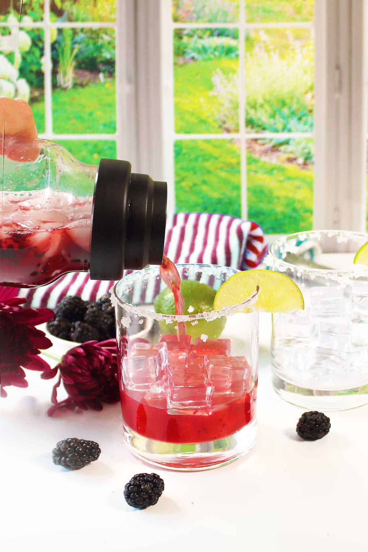 Pouring margarita into glass with ice.
