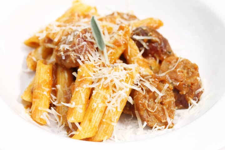 Closeup of bowl of sausage pasta with pumpkin sauce.