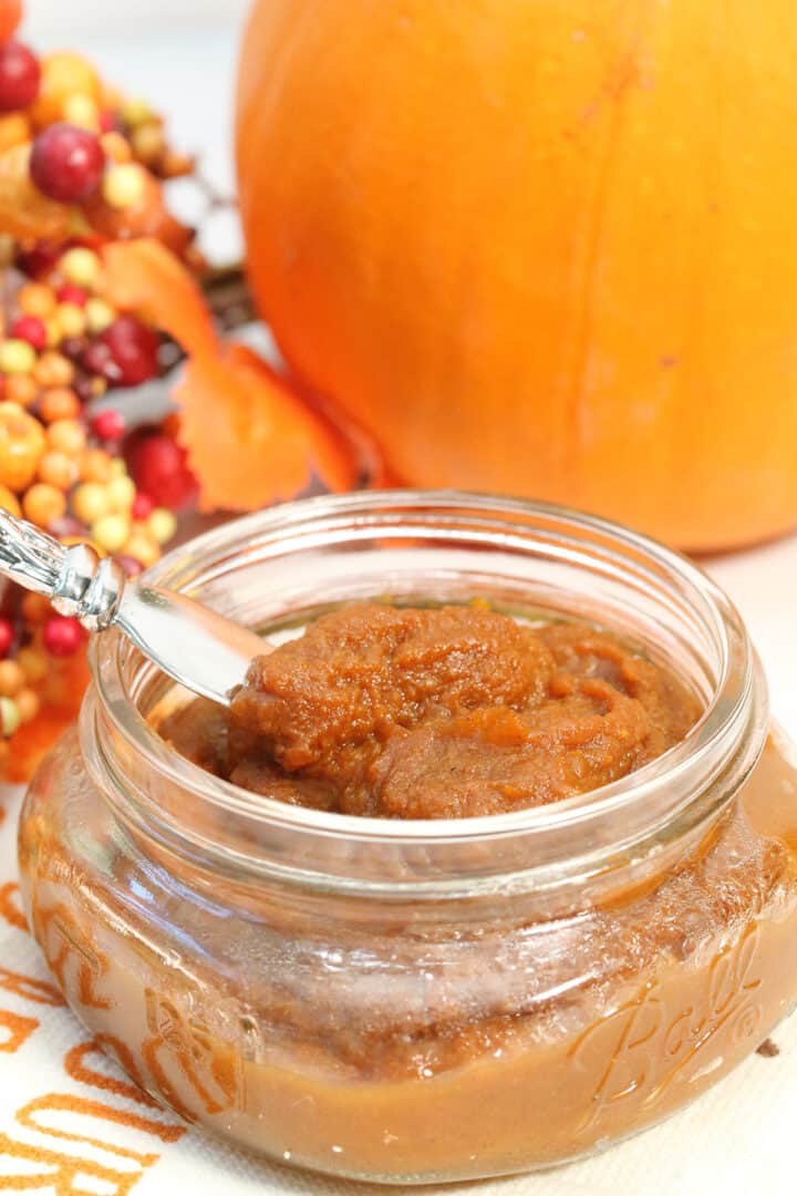 Jar of pumpkin butter with spreader inside.