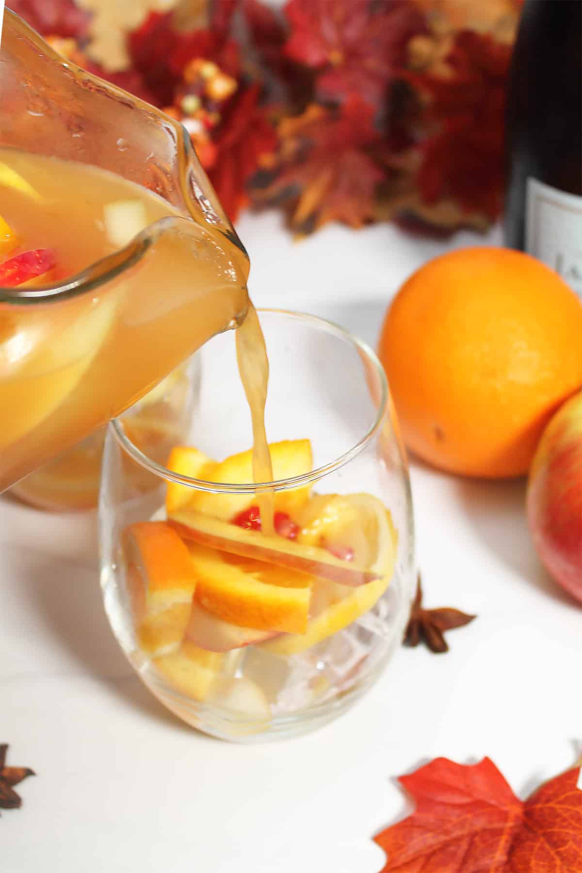 Adding cider to glass of ice ad fruit.