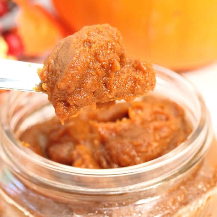 Scoop of pumpkin butter above full jar.