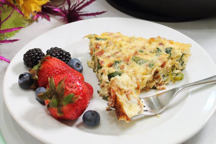 Serving on white plate with bite on fork and fruit on the side.
