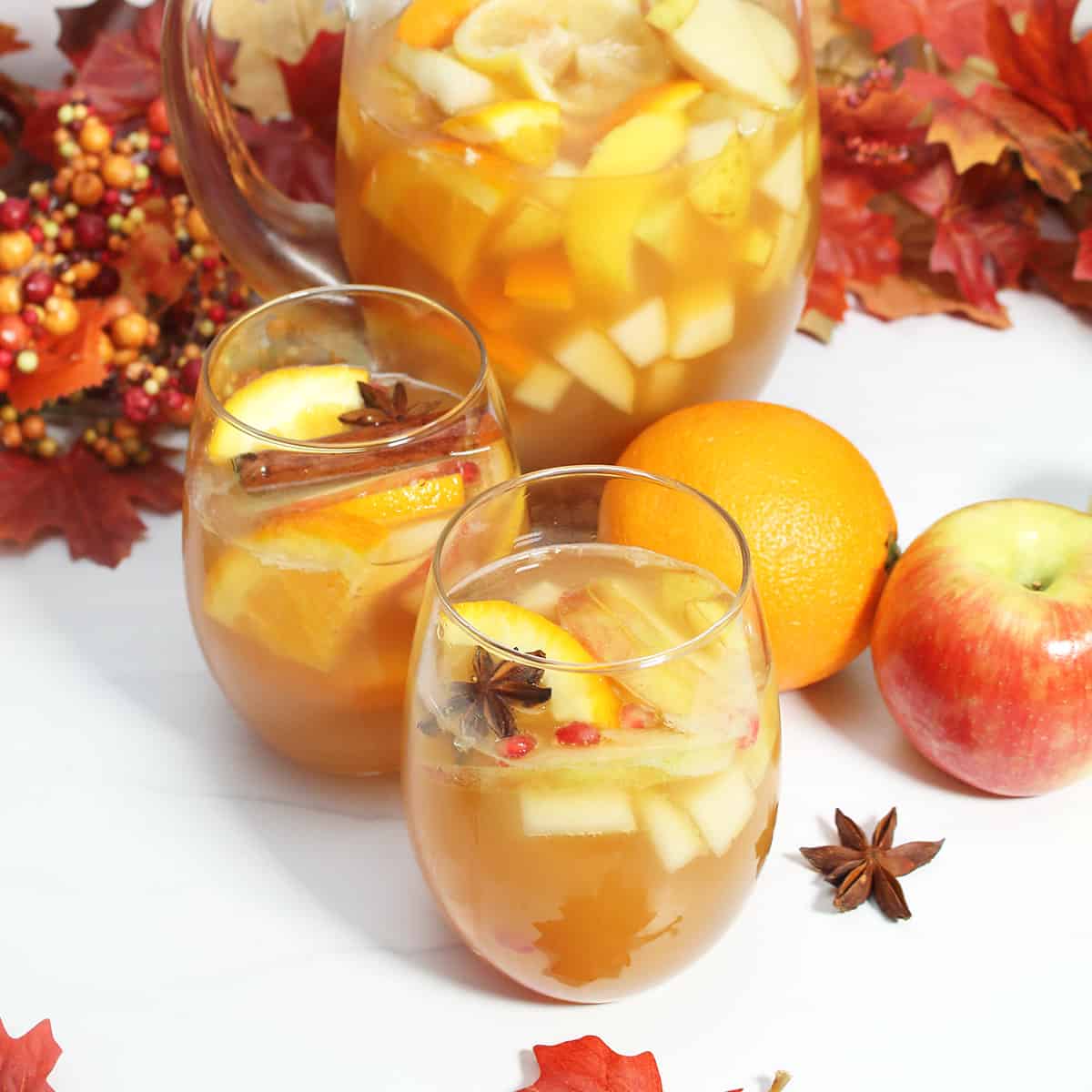 Two glasses filled with sangria with pitcher in back.