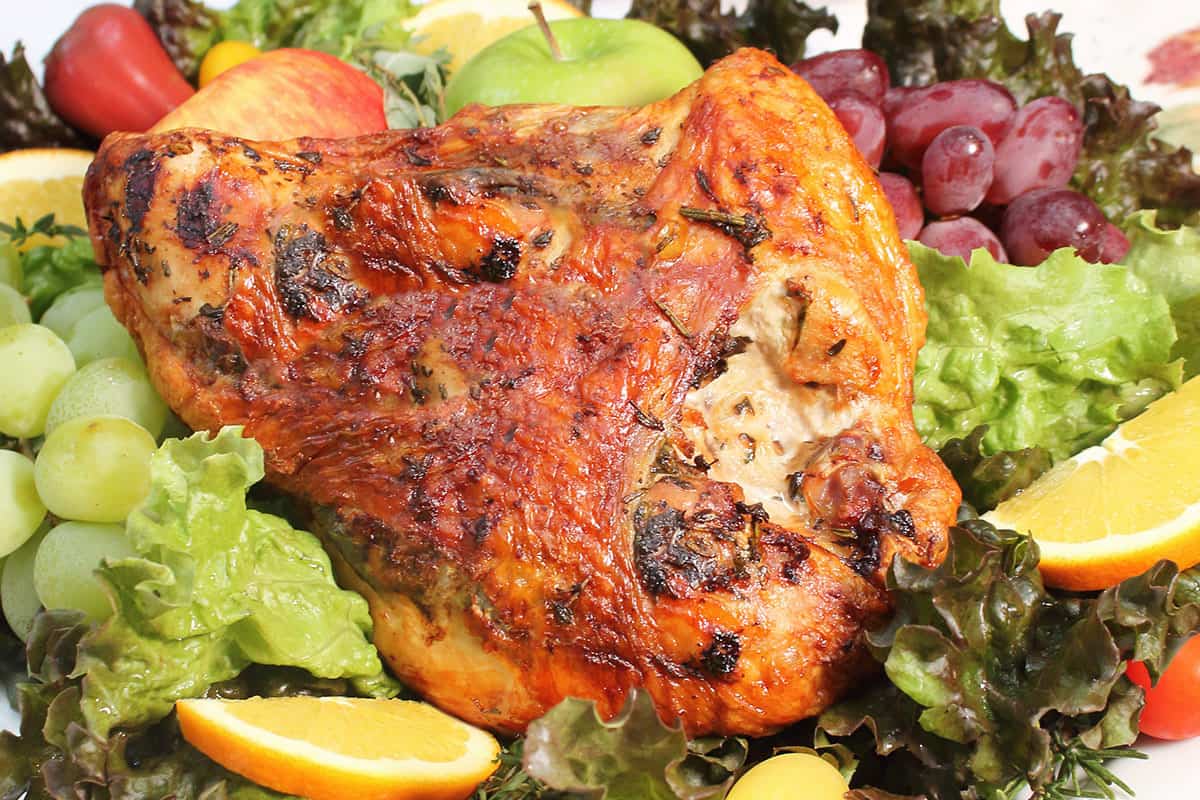Air Fried turkey breast with herb butter on platter with fruits and greens.