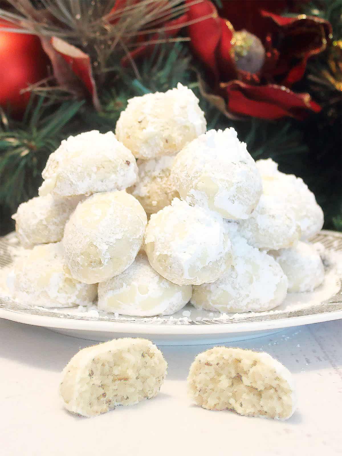 Brazil Nut Snowball Cookies piled on plate with halved one in front.