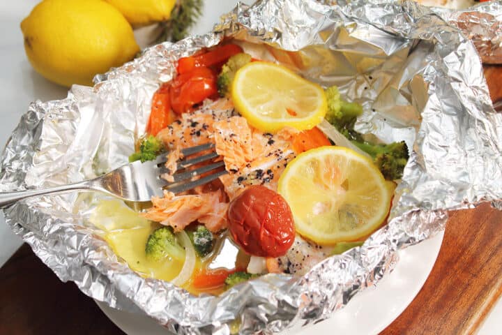Flaked salmon on fork in foil packet.