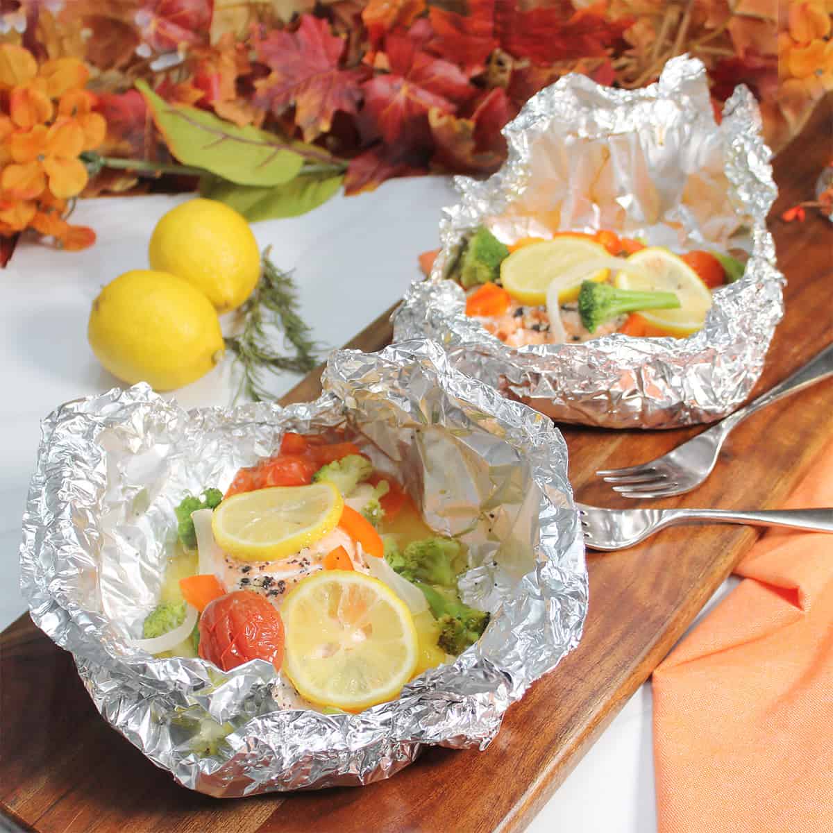 Two servings of foil baked salmon in foil packets.